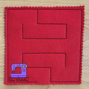 May include: Red felt square with a black stitched maze pattern. The maze is shaped like the letter "E". A purple sewing machine with the text "Sew Stitchy" is in the bottom left corner.