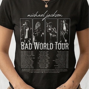 May include: Black t-shirt featuring a graphic of Michael Jackson's Bad World Tour. The design includes images of Jackson and tour dates. The text "michael jackson" is above the graphic.