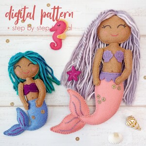 May include: A digital pattern for making two felt mermaid dolls. The larger mermaid has a pink tail and purple hair, while the smaller mermaid has a blue tail and turquoise hair. Both mermaids have brown skin and smiling faces.