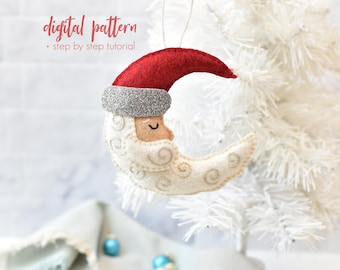 May include: A felt Christmas ornament shaped like a crescent moon with a Santa hat. The moon is cream-colored with embroidered details, a tan face, and a red hat with a silver glitter band. The text "digital pattern + step by step tutorial" is at the top.