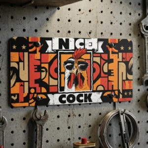 May include: A rectangular metal sign with a rooster wearing sunglasses, the word "NICE" above the rooster, and the word "COCK" below. The sign has a colorful geometric design in orange, black, and white.