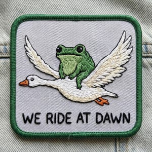 We Ride at Dawn - Frog on Goose Patch | Funny Meme Embroidered Badge | Duck & Frog Iron-On for Jackets, Bags, Vests