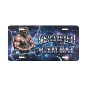 May include: Black license plate featuring a muscular rat lifting a barbell against a cosmic background with lightning. The text "CERTIFIED GYM RAT" is displayed in chrome lettering.