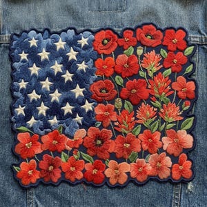 May include: A rectangular embroidered patch featuring a dark blue field with white stars on the left side and a vibrant arrangement of red and orange flowers with green leaves on the right side, all stitched onto a blue denim fabric background.