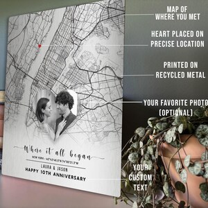 May include: A personalized metal map print featuring a couple's photo and the text "Where it all began." The map highlights a specific location with a heart, printed on recycled metal. Includes custom text and is ideal for anniversaries.