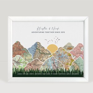 May include: White framed art print featuring a mountain range design. The mountains are composed of vintage map sections, with a yellow sun and birds above. Text reads "Kristen & Nick Adventuring Together Since 2015" and city names below.