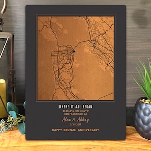 May include: A rectangular wall plaque featuring a copper-toned map of San Francisco with a black heart icon. The text reads: WHERE IT ALL BEGAN, 37.7749 N, 122.4194 W, SAN FRANCISCO, CA, Alex & Abbey, 7/16/2017, HAPPY BRONZE ANNIVERSARY.