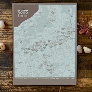 May include: A map of New Hampshire's 4000 Footers, showing the location of the mountains. The map is printed on a light brown background with a quote from Edmund Hillary: "It is not the mountain we conquer but ourselves."