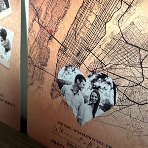 May include: A copper-colored map of New York City with a heart-shaped overlay featuring a couple. The map includes the coordinates "40&deg;42'48.8"N 74&deg;00&prime;21.3"W" and the text "Where it all..." and "HAPPY DAVID".