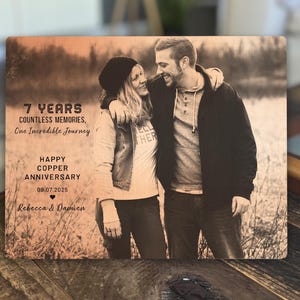 May include: A wood engraved sign with a sepia toned photo of a couple. The text reads "7 Years Countless Memories, One Incredible Journey Happy Copper Anniversary 09.07.2025 Rebecca & Damien".
