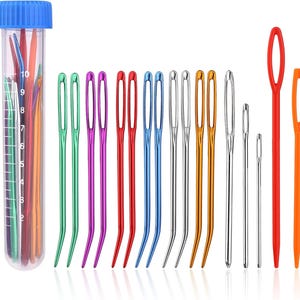 Puede incluir: Una colección de agujas coloridas para diversas manualidades. La imagen muestra un tubo transparente con una tapa azul lleno de agujas variadas, junto a una fila de agujas individuales en verde, morado, rojo, azul, plateado y dorado, más dos agujas naranjas y rojas.