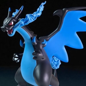 May include: A detailed figurine of a dragon-like creature with black and blue coloring. The figure has large blue wings, a long neck, and a fiery blue tail. The dragon is in a dynamic pose, with its mouth open.