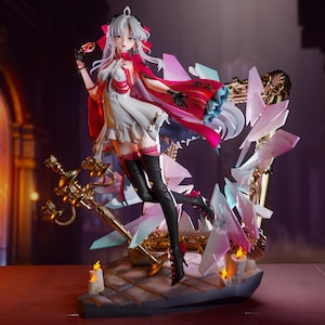 May include: A detailed figurine of a female character in a white dress and red cape, holding a mask. The figure is set against a backdrop of a decorative frame with crystal-like accents and a golden sword. The base includes lit candles.