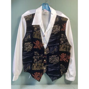May include: A white collared shirt with long sleeves, paired with a black vest. The vest features a floral and script design in shades of gold, red, and blue. Gold buttons adorn the front of the vest, adding a touch of elegance.