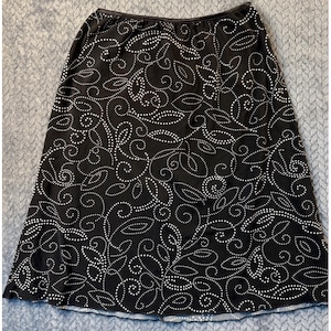 May include: A white ceramic mug with a black handle and the text "But First, Coffee" in a handwritten style. The mug is on a white surface. The mug is approximately 4 inches tall.