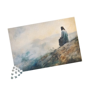 May include: A jigsaw puzzle featuring a watercolor painting of a figure in a robe seated on a hillside, overlooking a misty landscape. The puzzle is mostly assembled, with a small section of loose pieces.