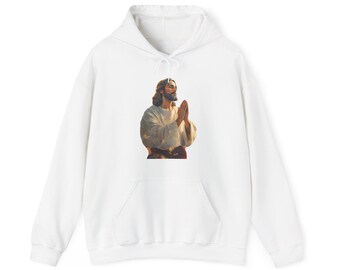 May include: White hooded sweatshirt featuring a graphic of a person with long hair and a beard, with hands clasped in prayer. The graphic is in shades of brown, beige, and white. The sweatshirt has a front pocket and a drawstring hood.