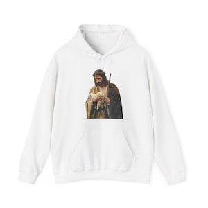 May include: White hoodie with a graphic print of a religious figure holding a lamb. The image is in shades of brown and beige. The sweatshirt has a front pocket and a drawstring hood.
