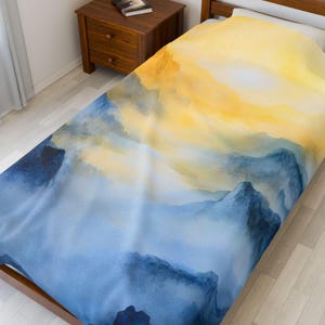 May include: A twin-sized duvet cover featuring a watercolor design. The design showcases a gradient of colors, with a bright yellow upper portion transitioning into shades of blue. The blue hues create a mountain-like effect.