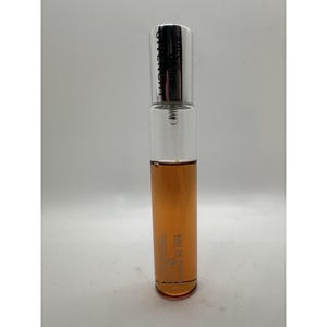 May include: A clear glass perfume bottle with a silver cap. The bottle contains a light brown liquid. The text "GIVENCHY" is printed vertically on the cap. The words "EAU DE PARFUM" are printed on the bottle.