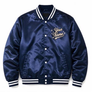 May include: A navy blue satin varsity jacket featuring a white snap-button front closure, ribbed collar, cuffs, and hem with white stripes. The chest displays the embroidered text Your Name in a cursive font surrounded by four-pointed star icons.