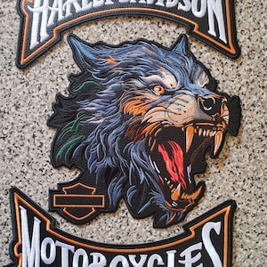 May include: Embroidered Harley-Davidson motorcycle patch featuring a snarling wolf with blue, orange, and red details. The patch includes the Harley-Davidson logo and the word "MOTORCYCLES" in white lettering with orange and black borders.