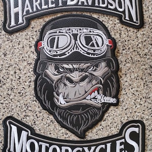 Puede incluir: Parches bordados de Harley-Davidson y Motorcycles. El parche central presenta un gorila con gafas y casco, con un cigarro en la boca. Los parches son negros, blancos y grises.