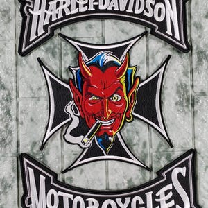 Puede incluir: Parche bordado con el logo de Harley-Davidson y el texto "Motorcycles". El diseño central es un diablo rojo con pelo azul, ojos amarillos y un cigarro, sobre una cruz negra. Letras blancas sobre fondo negro.