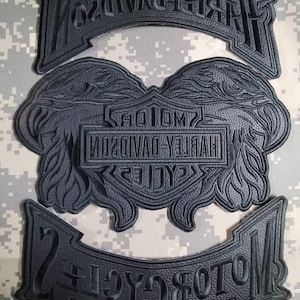 Puede incluir: Parches de cuero negro con el logotipo y el texto de Harley-Davidson. Los parches incluyen el logotipo de Harley-Davidson con alas y dos parches en forma de banner con las palabras "Harley-Davidson Motor Cycles".
