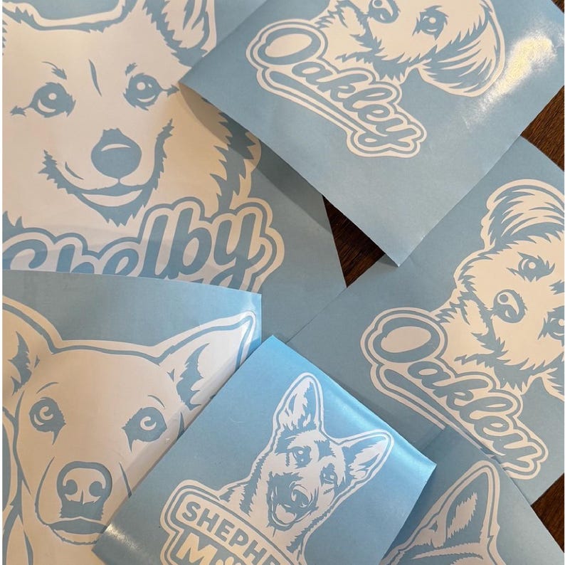 Puede incluir: Varias pegatinas de vinilo azul claro con ilustraciones de l&iacute;neas blancas de caras de perros. Los dise&ntilde;os incluyen los nombres Oakley y Shelby en letra cursiva, y una pegatina presenta el texto Shepherd Mix bajo un retrato de perro.