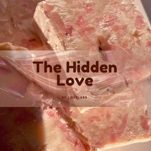 May include: Close-up of a light pink and white soap bar with pink floral inclusions. The text "The Hidden Love" is visible on the soap. The soap is made by LOV3LABS.