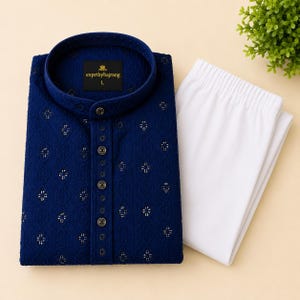 Puede incluir: Un conjunto de kurta bordado azul marino con cuello mandarín y cierre de botones, combinado con pantalones blancos. La camisa presenta un patrón floral y el texto "exprtbybajrang L" en una etiqueta.