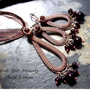 Peut inclure: Un collier en fil de cuivre avec un pendentif composé de trois boucles en forme de larme ornées de perles de verre rouge foncé. Le collier est rehaussé d'un ruban brun.