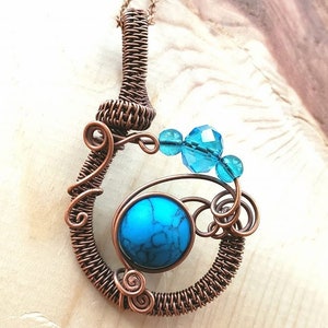 May include: A copper wire pendant necklace with a turquoise stone and blue glass beads. The pendant is in the shape of a swirl.