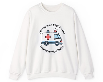 May include: White crewneck sweatshirt with a graphic of an ambulance and the text "I Became an EMT for the Free Wee Woo Rides". The ambulance is white with a red cross and blue accents.