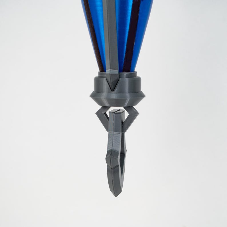 May include: A 3D-printed object in shades of grey and blue, featuring a conical top with blue and grey vertical stripes. It has a geometric handle with a circular opening. The object is set against a white backdrop.