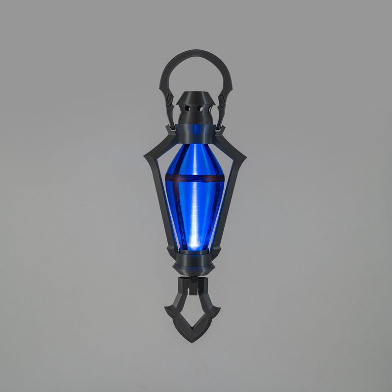 May include: A striking lantern with a vibrant blue interior light. The lantern features a black, decorative frame and a handle. The design is symmetrical, with a pointed base and a rounded top. The overall aesthetic suggests a fantasy or science fiction theme.