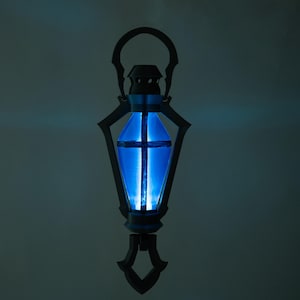 May include: An elaborate lantern with a bright blue interior. The lantern features a handle, decorative side panels, and a base. The blue light is a strong contrast to the dark frame, creating a striking visual.