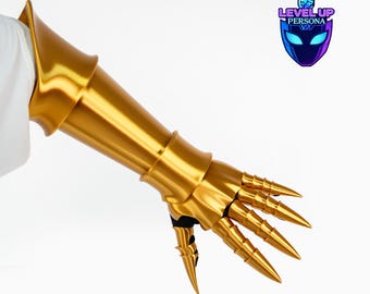 May include: A metallic gold gauntlet featuring a flared forearm guard and articulated finger plates ending in sharp, pointed tips. The piece includes a black fabric base and displays the logo Level Up Persona with an upward arrow icon.