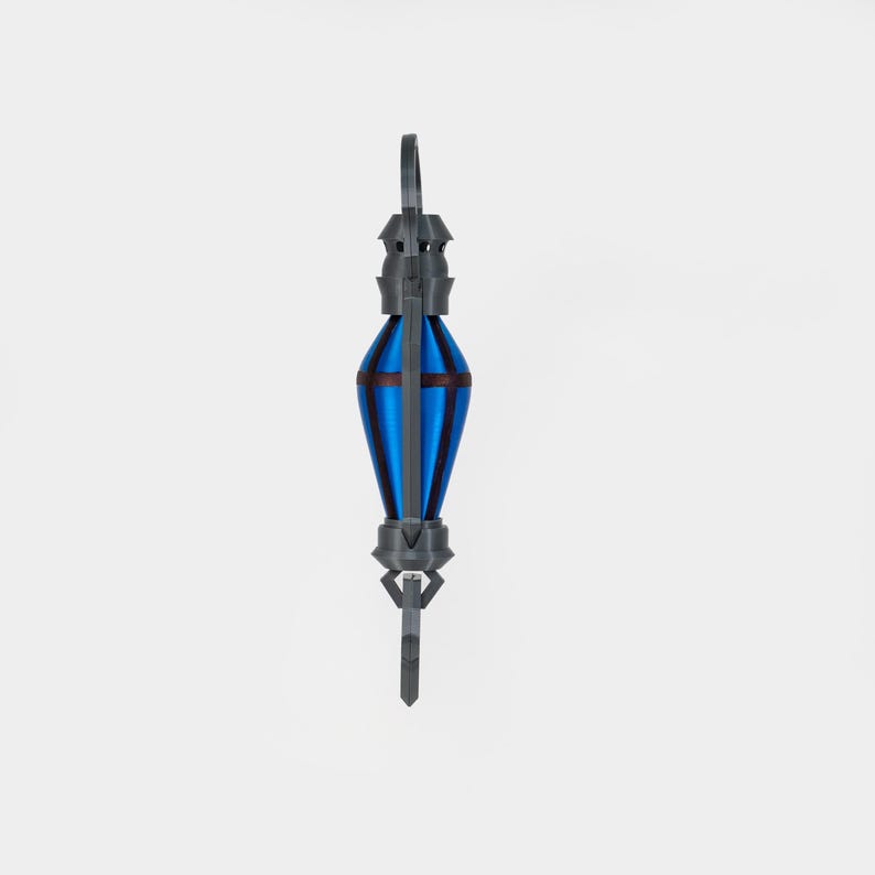 May include: A 3D-printed pendant with a blue and brown central section. The pendant features a grey, geometric design at the top and bottom, with a loop for hanging. The central section is a vibrant blue with brown accents.