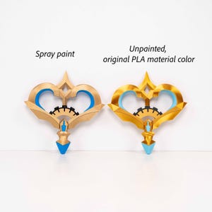 May include: Two decorative key-shaped objects, one spray painted and one unpainted. Both have a gold finish with blue accents and a black gear-like detail. The text "Spray paint" and "Unpainted, original PLA material color" are visible.