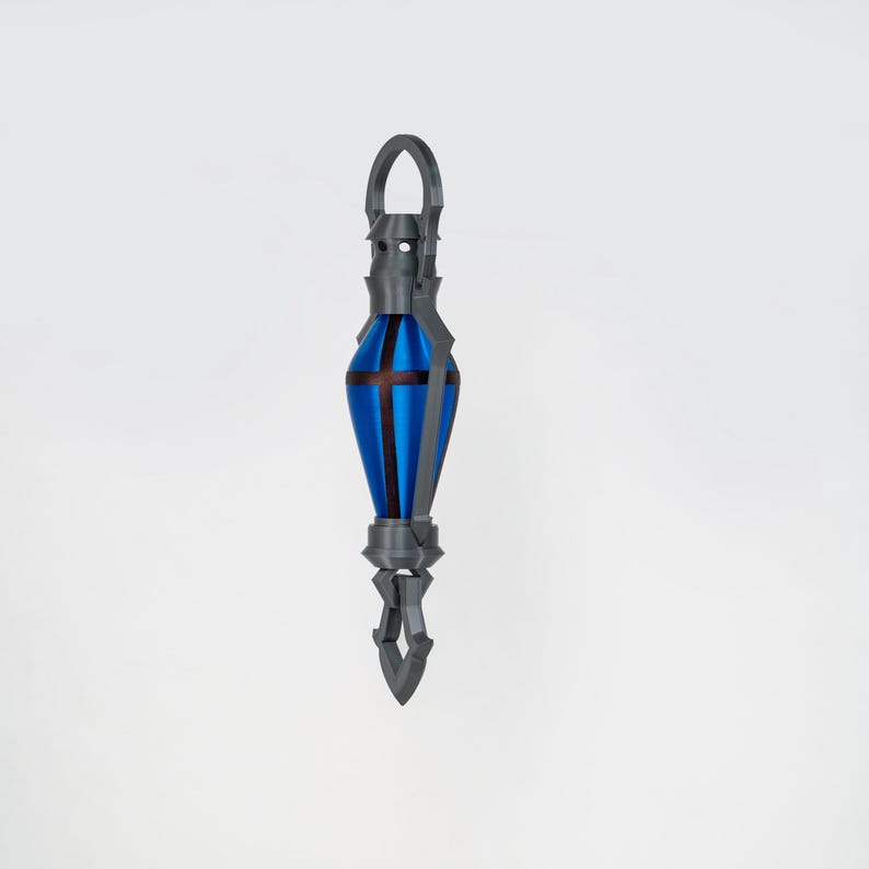 May include: A blue and grey decorative pendant with a geometric design. The pendant has a teardrop shape with a cross design and a loop at the top. The pendant is approximately 15 cm long.
