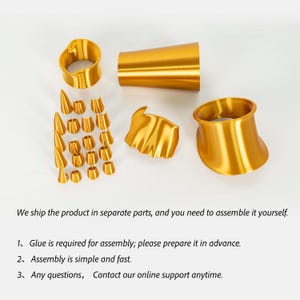 Puede incluir: Un conjunto de componentes met&aacute;licos de color dorado que incluye dos anillos grandes acampanados, una pieza cil&iacute;ndrica c&oacute;nica, un segmento ondulado y diecis&eacute;is piezas peque&ntilde;as c&oacute;nicas y cil&iacute;ndricas, que requieren ensamblaje con pegamento.