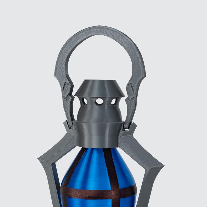 May include: A grey lantern with a blue and brown bottle-shaped base. The lantern has a handle and decorative arms. The top has three circular holes. The base has a metallic blue finish with brown stripes.