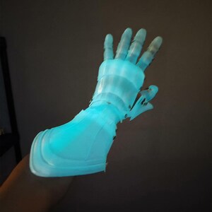 May include: A glowing, light blue prosthetic hand, possibly 3D-printed, with a detailed design. The hand is illuminated, creating a futuristic and technological aesthetic. The fingers are articulated, and the overall design suggests a focus on functionality and form.