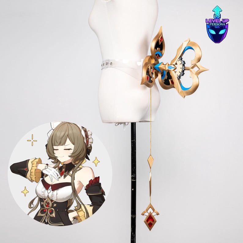 May include: A gold and blue cosplay accessory, possibly a key or emblem, attached to a clear belt. The design features intricate details and a dangling chain with diamond and gem-shaped pendants. A cartoon image is in the lower left corner.