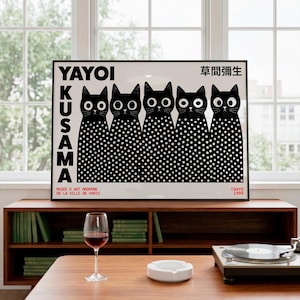 May include: A framed rectangular art print featuring five black cats with large white eyes and white polka dot bodies. The text YAYOI KUSAMA is printed vertically on the left, with Japanese characters, MUSEE D ART MODERNE DE LA VILLE DE PARIS, and TOKYO 1995.