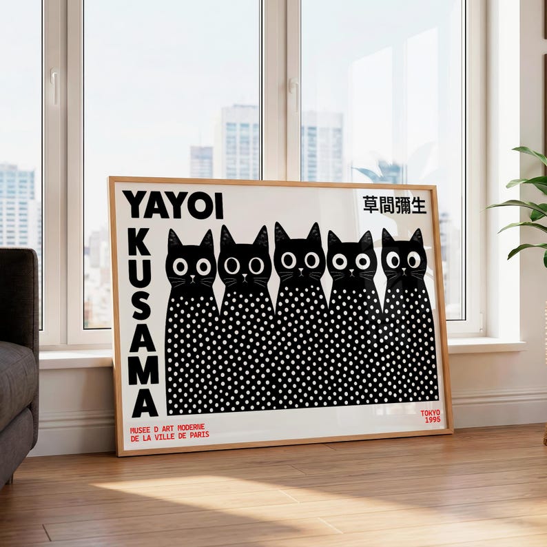 May include: A rectangular framed art print featuring five black cats with white polka-dot bodies and large white eyes. The text reads YAYOI KUSAMA, 草間彌生, MUSEE D ART MODERNE DE LA VILLE DE PARIS, and TOKYO 1995. The print has a white background and a light wood frame.