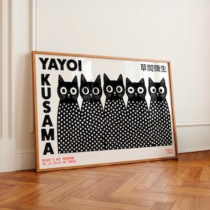 May include: A framed art print featuring five black cats with large white eyes and white polka-dot bodies. The text reads YAYOI KUSAMA, MUSEE D ART MODERNE DE LA VILLE DE PARIS, TOKYO 1995, and Japanese characters. The print is set in a light wood frame.
