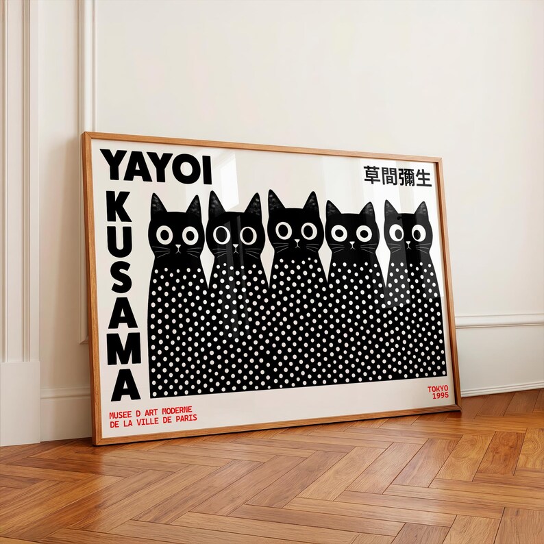 May include: A framed art print featuring five black cats with large white eyes and white polka-dot bodies. The text reads YAYOI KUSAMA, MUSEE D ART MODERNE DE LA VILLE DE PARIS, TOKYO 1995, and Japanese characters. The print is set in a light wood frame.